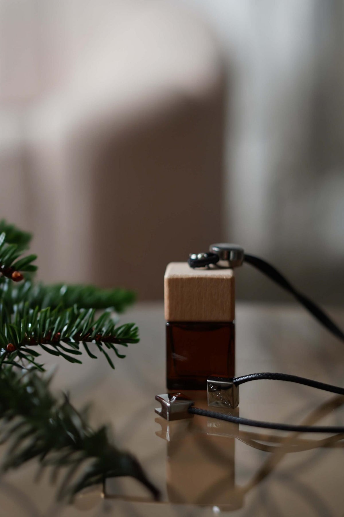 Άρωμα αυτοκινήτου Christmas Tree BY VELCHEVA 10ml σε γυάλινο μπουκάλι amber με ξύλινο καπάκι και μαύρο κορδόνι, δίπλα σε κλαδί έλατου