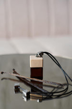 Άρωμα αυτοκινήτου Tobacco Vanilla BY VELCHEVA 10ml σε γυάλινο μπουκάλι amber με ξύλινο καπάκι και μαύρο κορδόνι, δίπλα σε λοβούς βανίλιας
