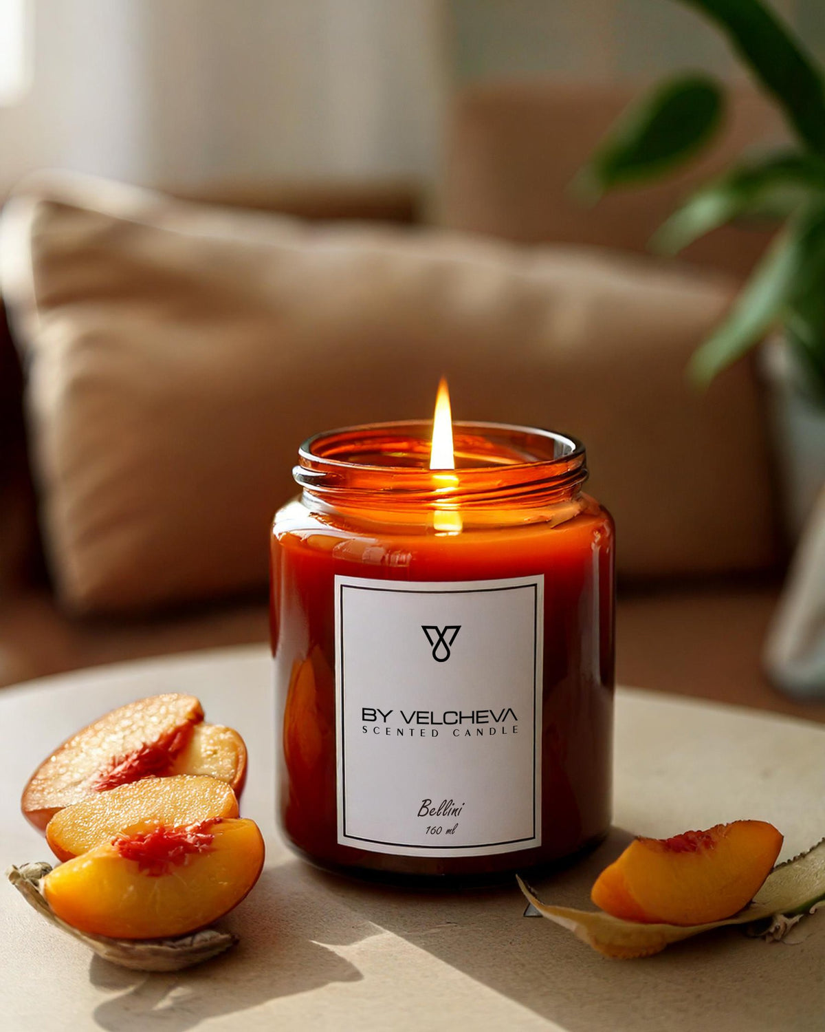 Αρωματικό κερί Bellini BY VELCHEVA 160ml σε γυάλινο βάζο amber, αναμμένο, με φέτες ροδάκινου δίπλα
