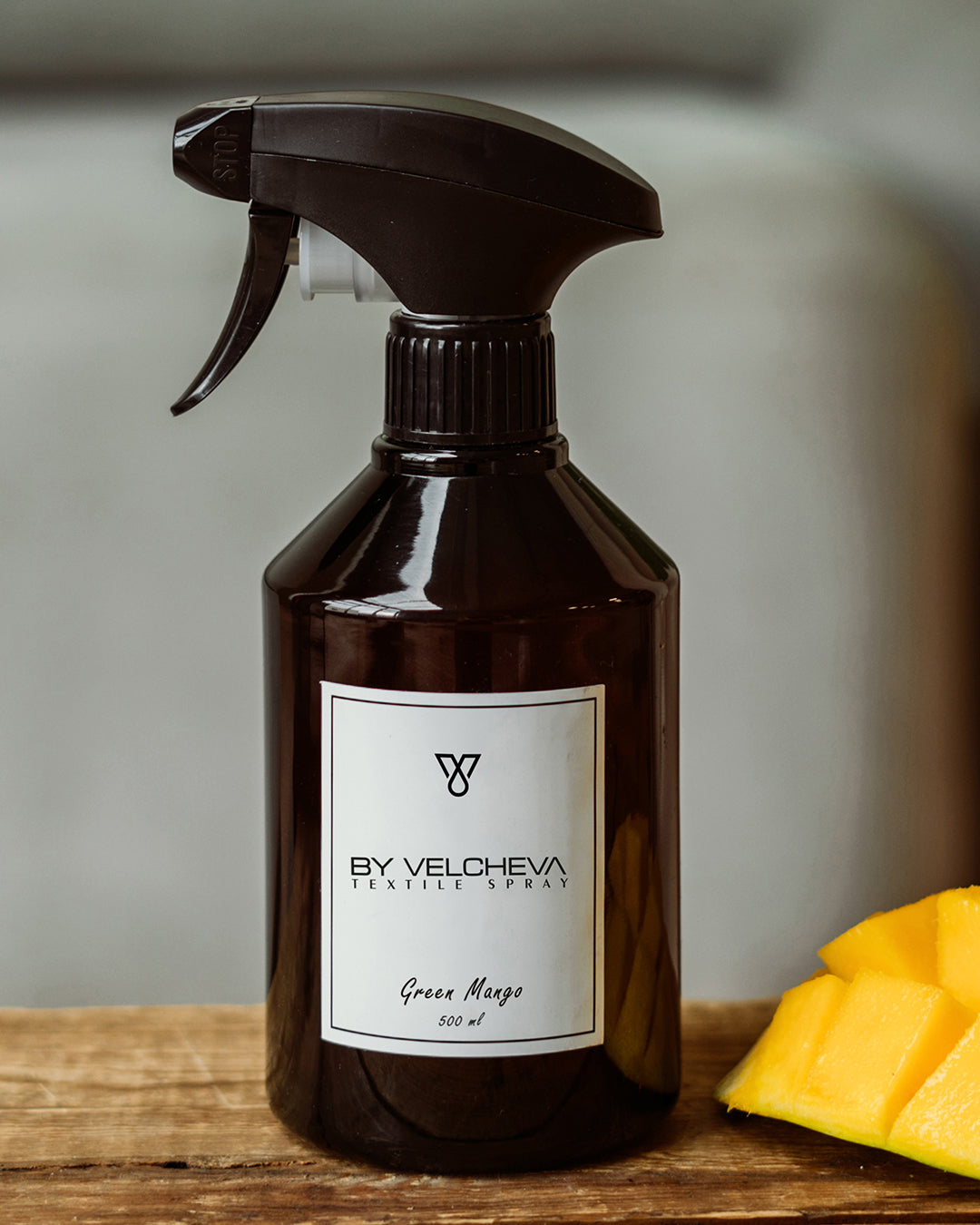 Αρωματικό σπρέι υφασμάτων Green Mango BY VELCHEVA 500ml σε καφέ μπουκάλι με αντλία ψεκασμού, δίπλα σε κύβους φρέσκου μάνγκο