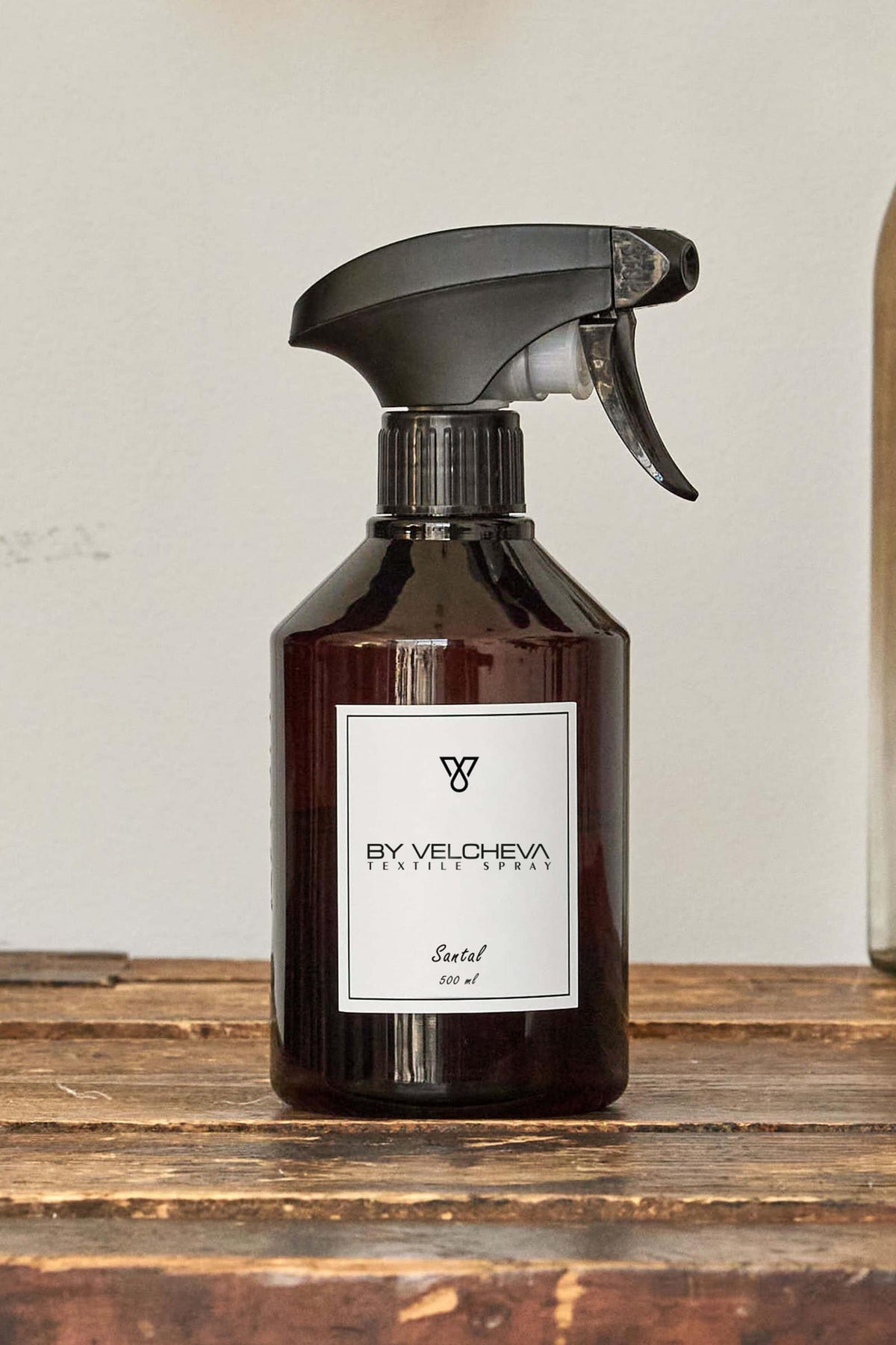 Αρωματικό σπρέι υφασμάτων Santal BY VELCHEVA 500ml σε καφέ μπουκάλι με αντλία ψεκασμού, πάνω σε ρουστίκ ξύλινη επιφάνεια